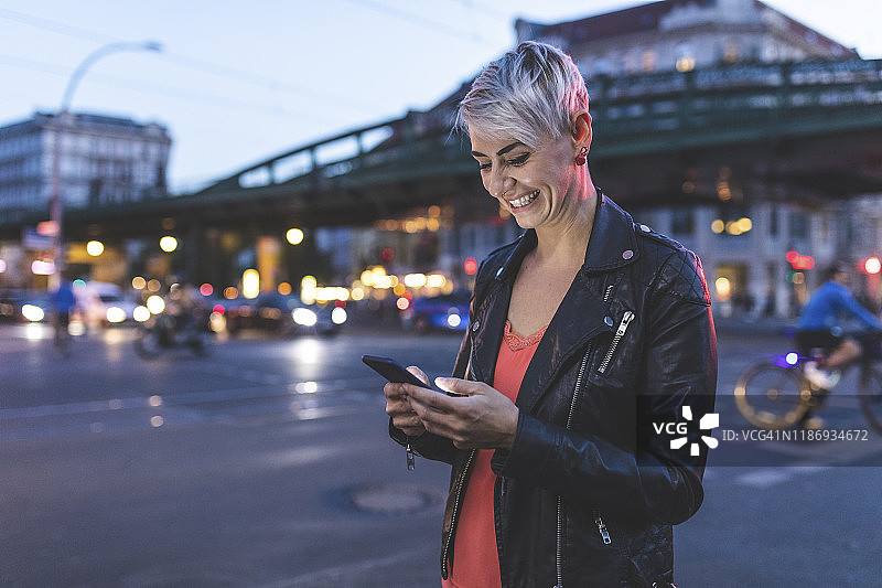 在德国柏林路边使用手机的欢笑金发女性肖像图片素材