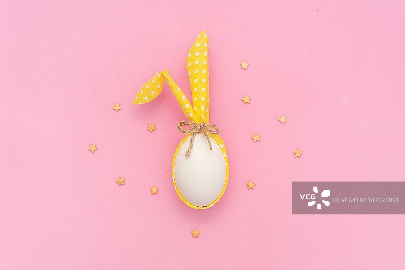 粉色背景上的兔子耳朵白色复活节彩蛋图片素材