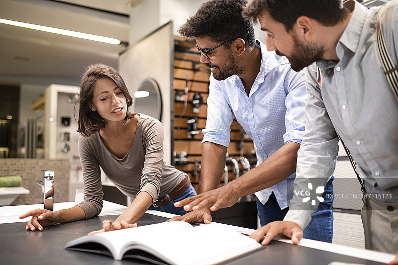 夫妻在卫浴瓷砖店与店主交谈，店主靠在桌子上介绍产品，桌上放着手机图片素材