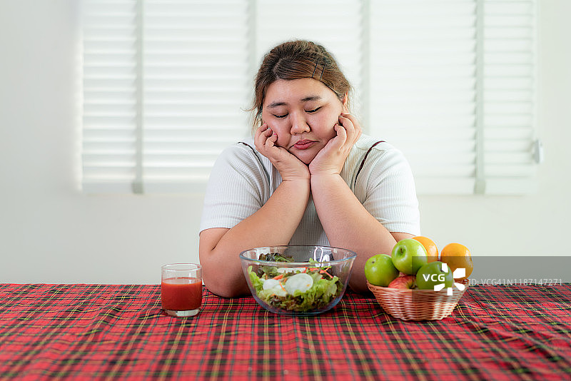 对绿色蔬菜沙拉感到厌烦的亚洲超重女人，营养、减肥和健康饮食理念图片素材