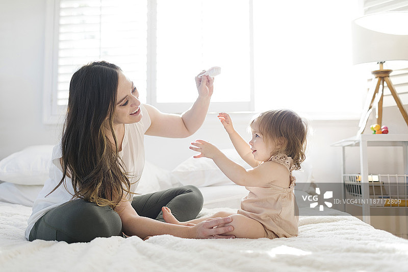 母亲和女儿在床上用发刷图片素材