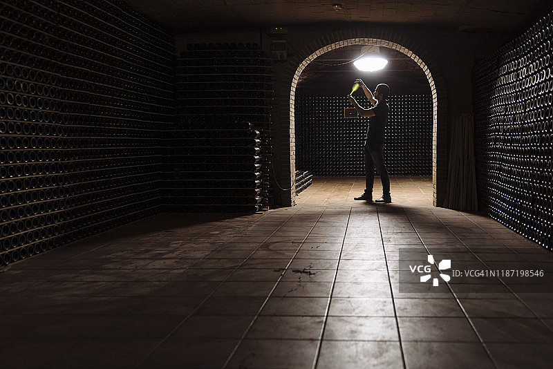 在酒窖里检查瓶子的男人图片素材