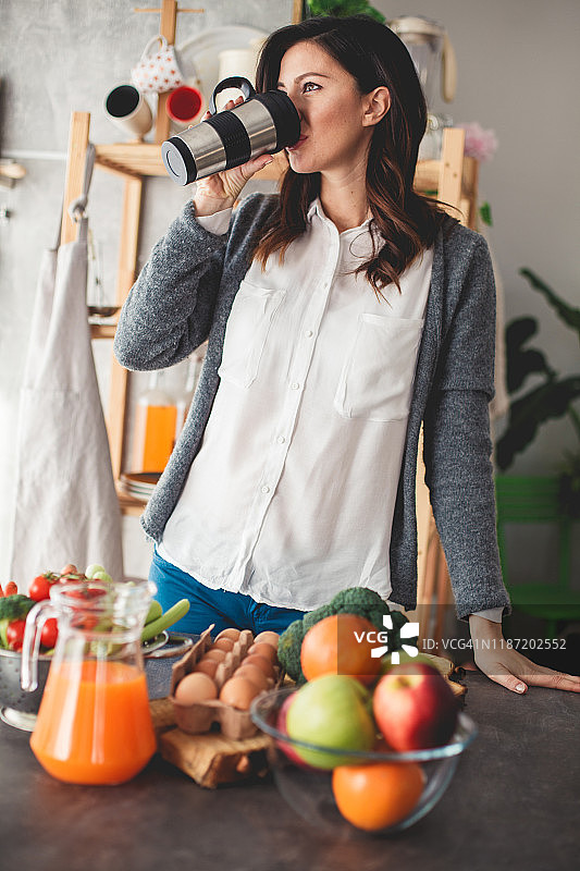 早上，快乐的中年妇女用保温杯喝咖啡图片素材