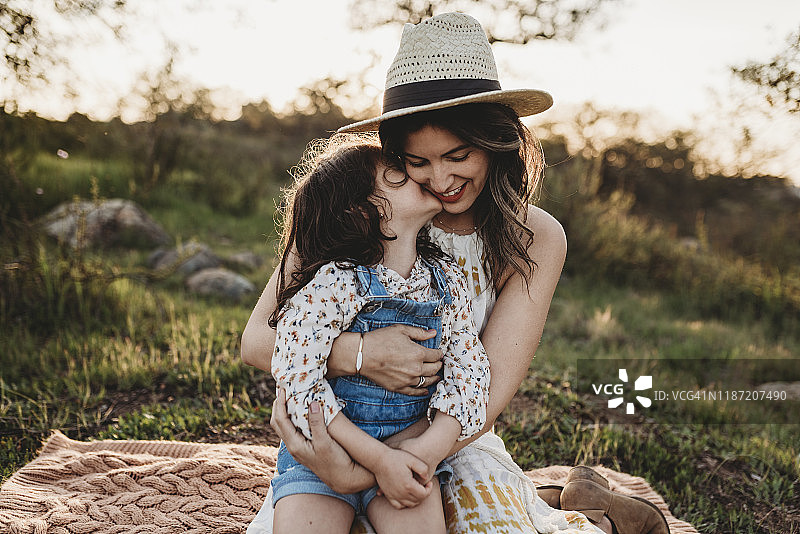 母亲和女儿坐在逆光草地上图片素材