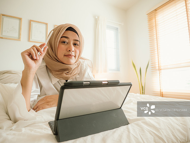 躺在床上使用平板电脑的年轻女人图片素材