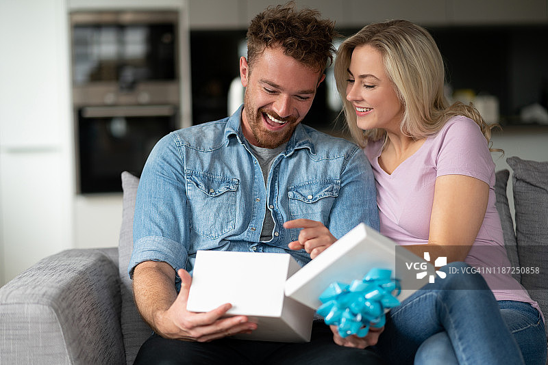 快乐的男人在家打开女朋友送的礼物图片素材