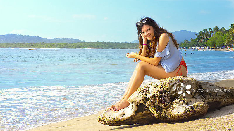 坐在海滩浮木上漂亮的少女图片素材