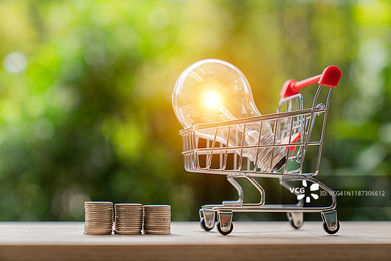 节能灯泡、硬币和购物车：节约、金融与购物概念图片素材