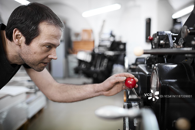 在老式印刷厂调整机器的男人图片素材
