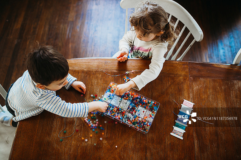 弟弟和妹妹在家捡珠子做手链图片素材