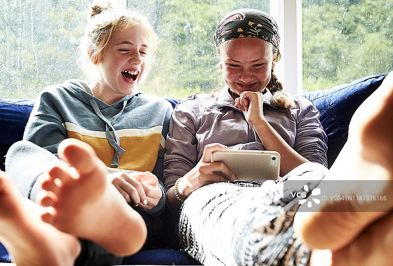 坐在沙发上看屏幕大笑的年轻女孩图片素材