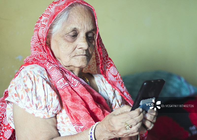 在家使用智能手机的印度老年妇女图片素材