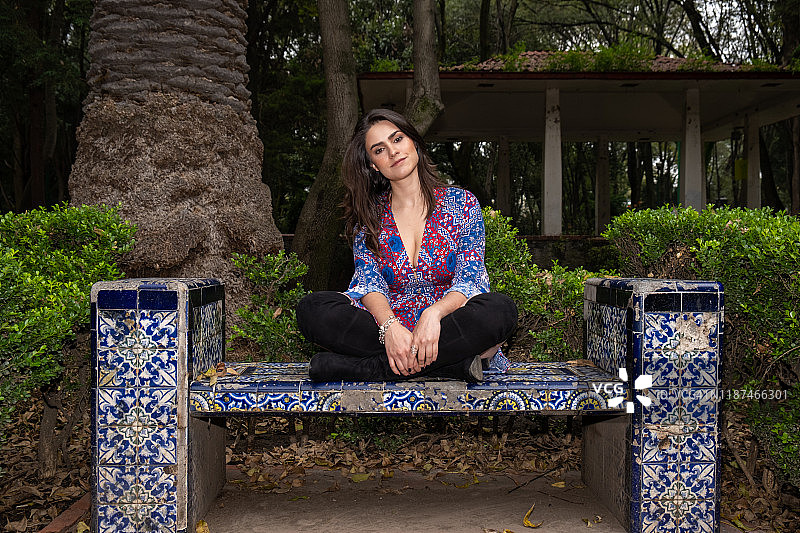 一位坐在墨西哥城墨西哥瓷砖长凳上的年轻西班牙裔女子图片素材