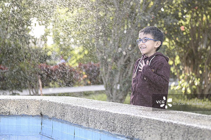 戴眼镜的快乐男孩在喷泉中图片素材