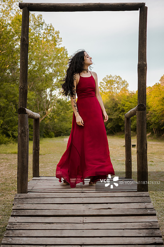 穿着红色连衣裙站在木制平台上的年轻女人。奇幻图片素材