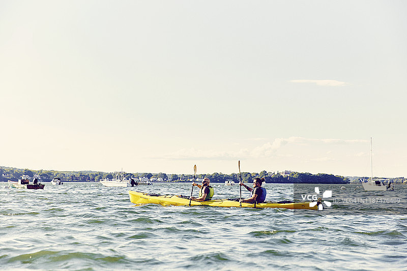 两个男人在缅因州卡斯科湾日落时分划双人皮划艇图片素材