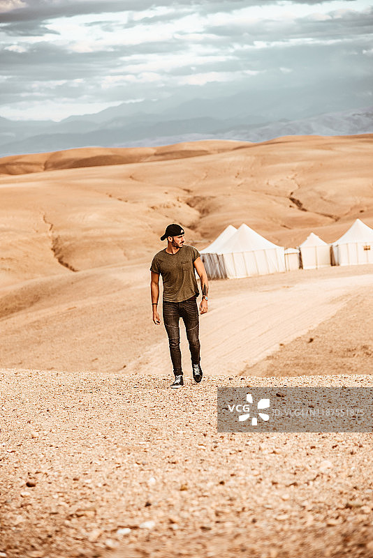 男人在摩洛哥的撒哈拉沙漠黄昏时行走图片素材