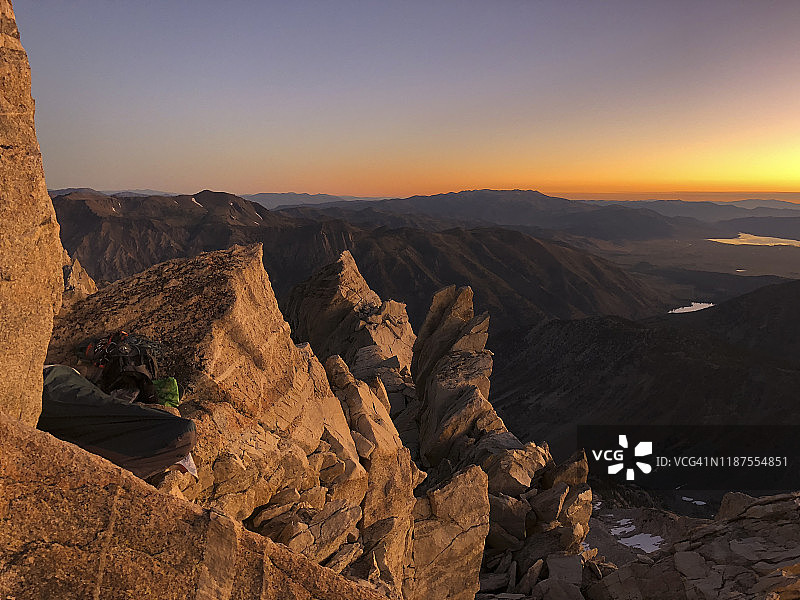 日出时分，男人睡在马特宏峰悬崖顶部的睡袋里，俯瞰锯齿岭图片素材