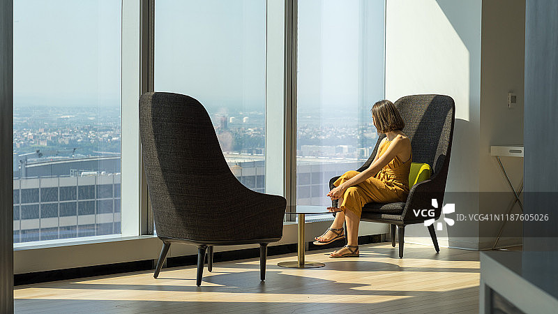 身穿黄色西装，在纽约巨型窗户边向外看的女人图片素材