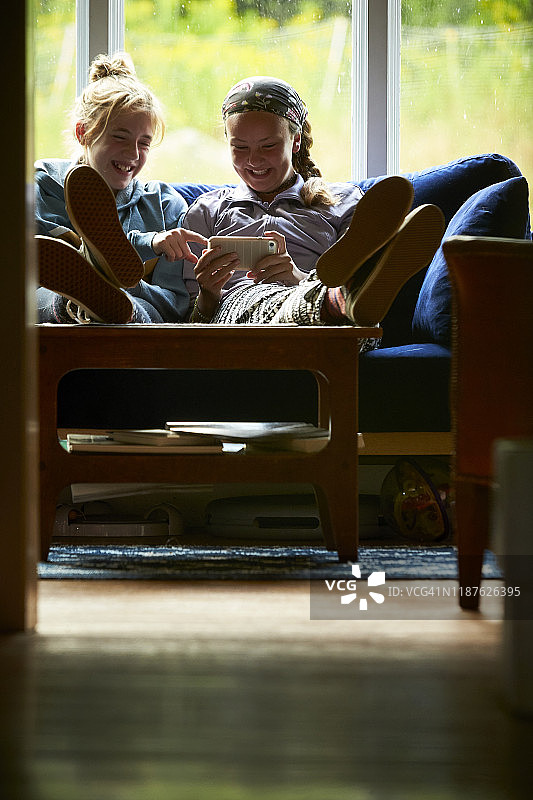 在沙发上看着手机欢笑的少女们图片素材