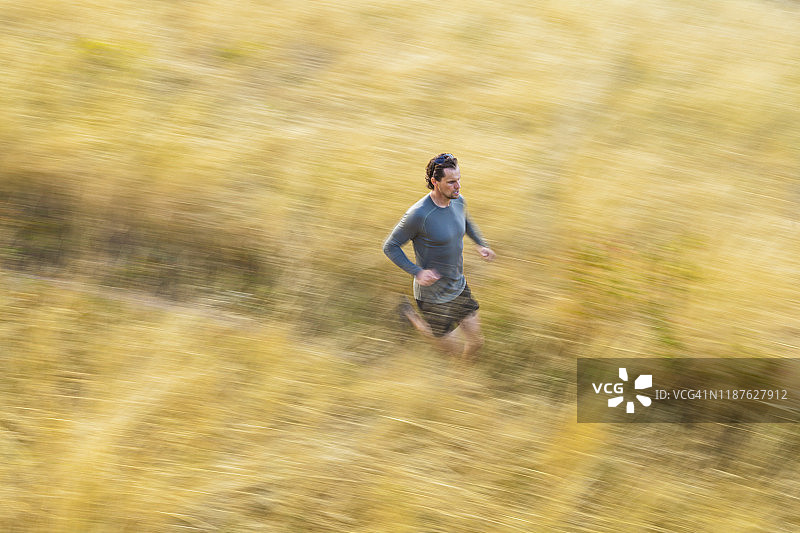 男人在科罗拉多州博尔德市的熊峡谷小径上穿过高高的草丛图片素材