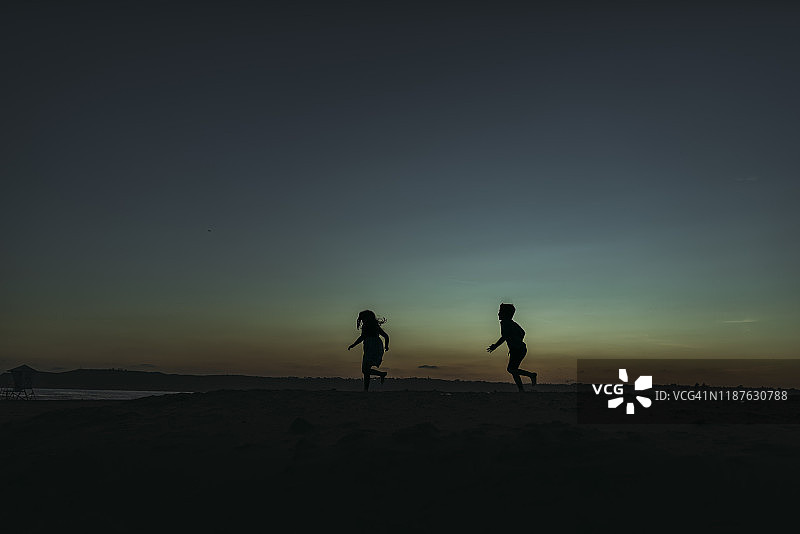 兄妹在黄昏时奔向大海的轮廓图片素材