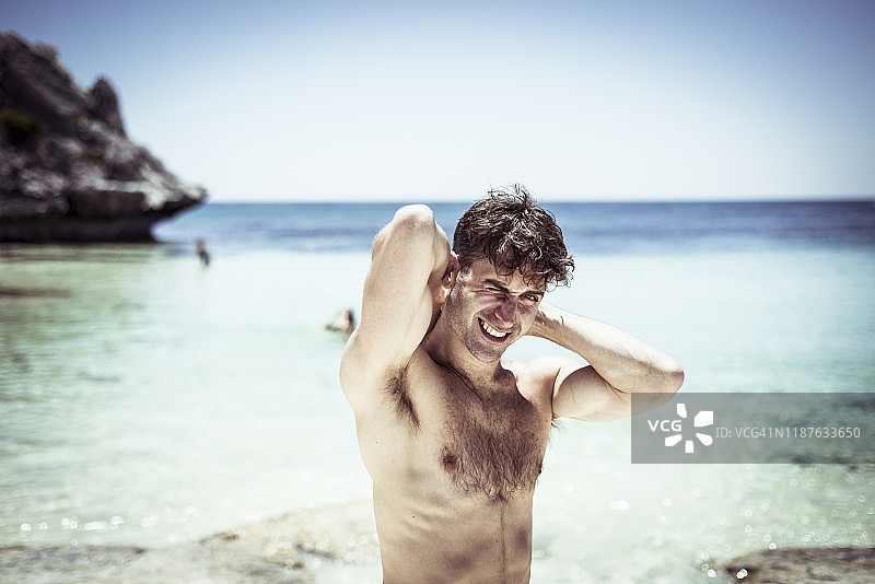 英俊男人在澳大利亚美丽蓝色海滩上伸展微笑图片素材