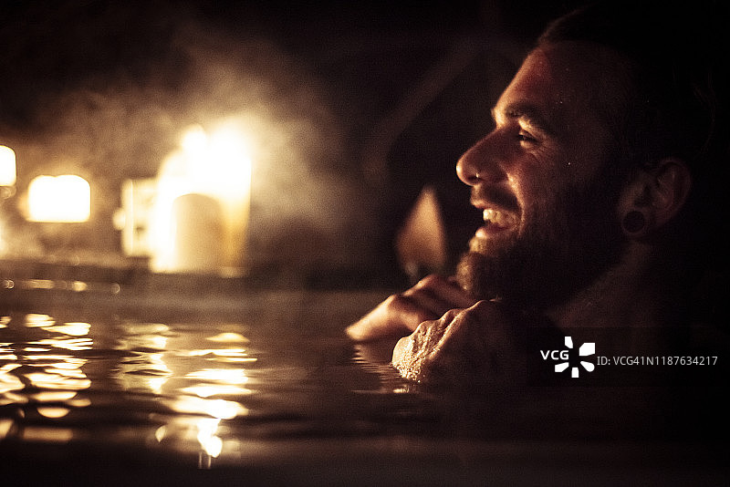 在户外浴缸中享受烛光和蒸汽的男人图片素材