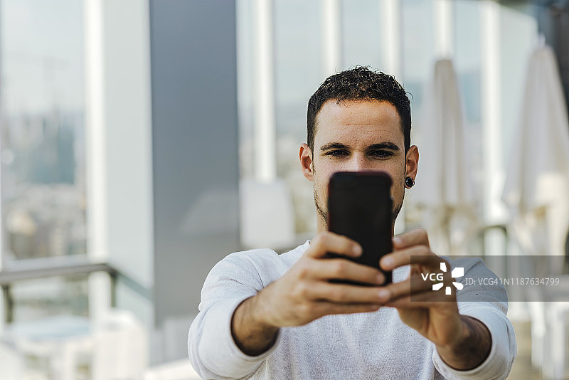 年轻男人用智能手机自拍图片素材