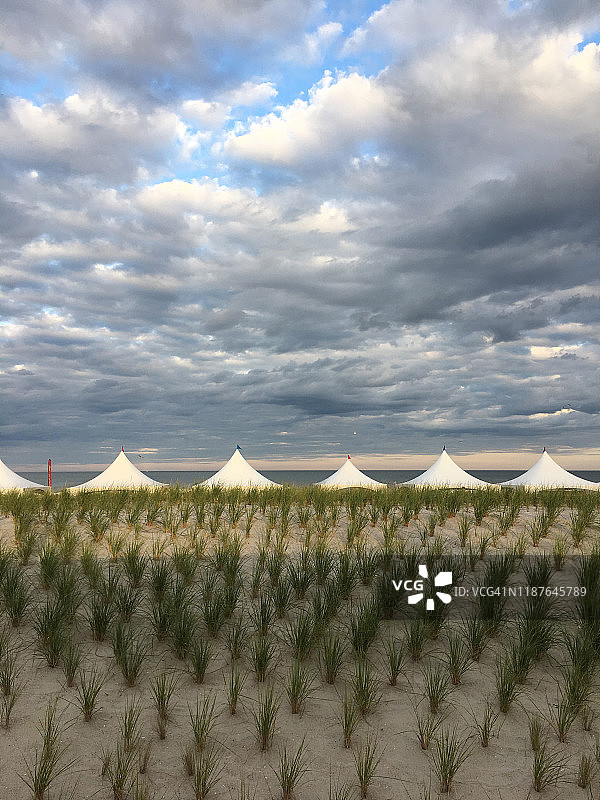 阳光明媚的戏剧天空下的白色帐篷图片素材