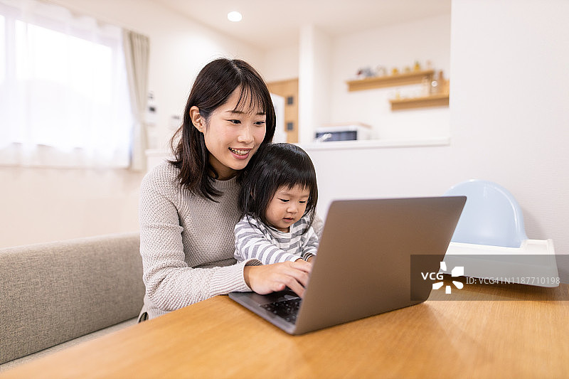 怀孕的母亲在家工作并照顾小女儿图片素材