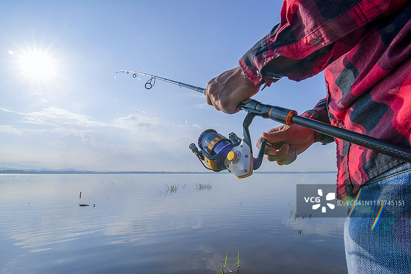 年轻人在日落时分从船上在湖上钓鱼图片素材