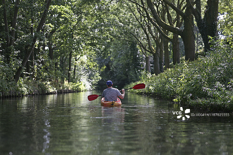一人在夏季的运河上划皮划艇图片素材