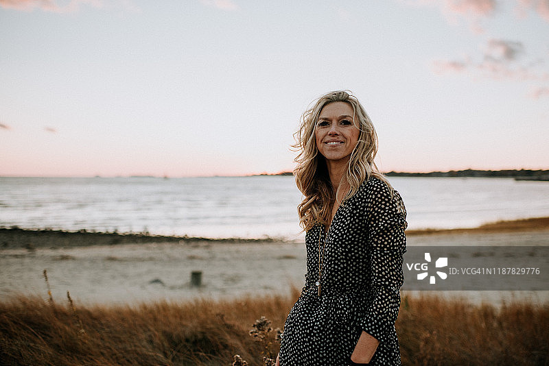 快乐的年轻女人在日落时分的海滩上图片素材
