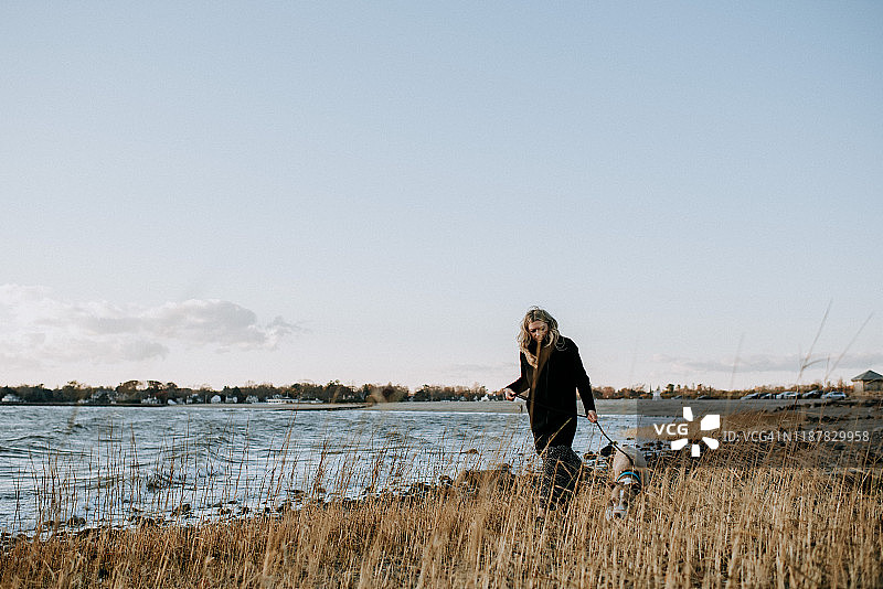 冬天女人在沙滩上遛狗图片素材