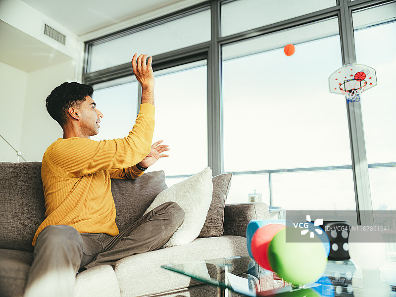玩室内玩具篮球的年轻印度男人图片素材