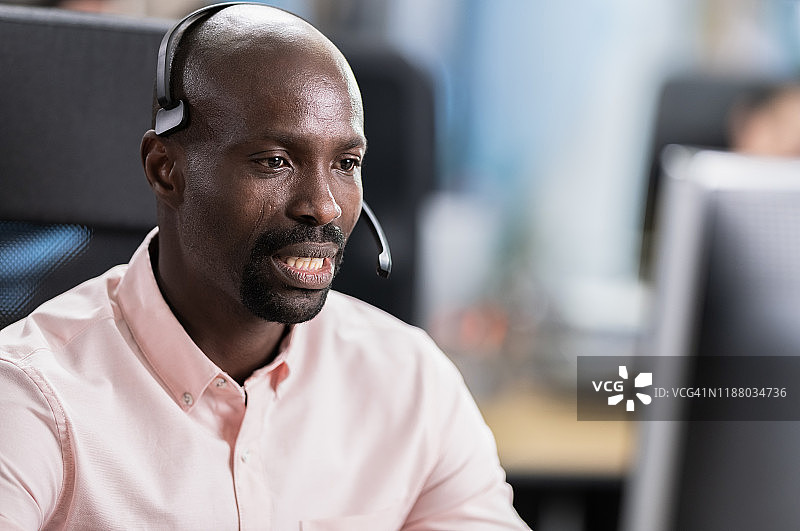 非裔美国男子通过耳机与客户交谈图片素材