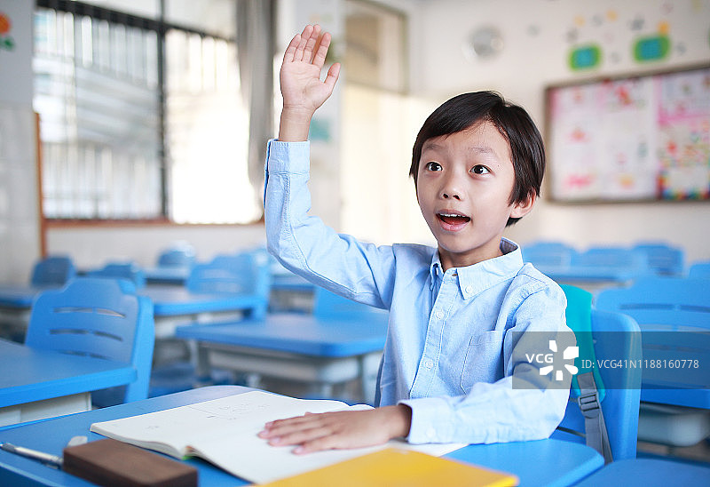 小男孩在教室里的书桌前看书图片素材