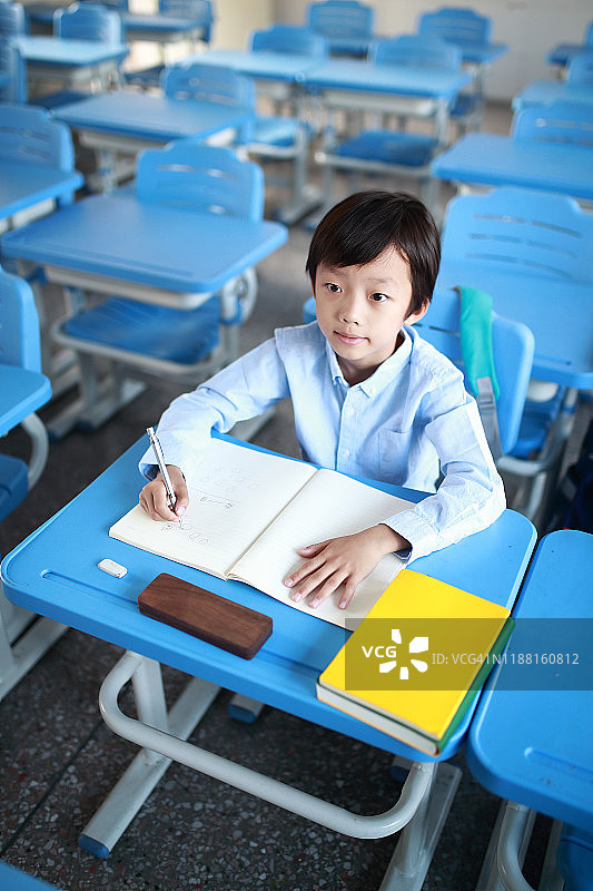 小男孩在教室里的书桌前看书图片素材