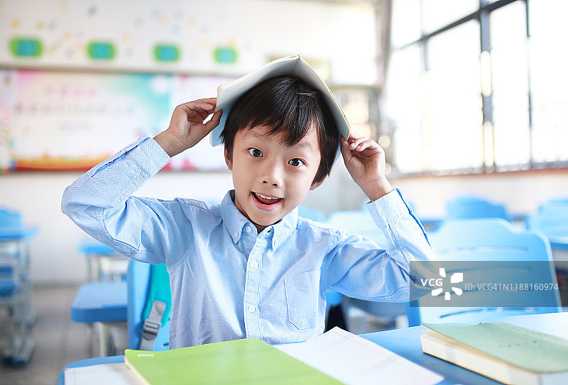 小男孩在教室里的书桌前看书图片素材