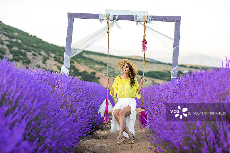 在薰衣草田中荡秋千的年轻女人图片素材