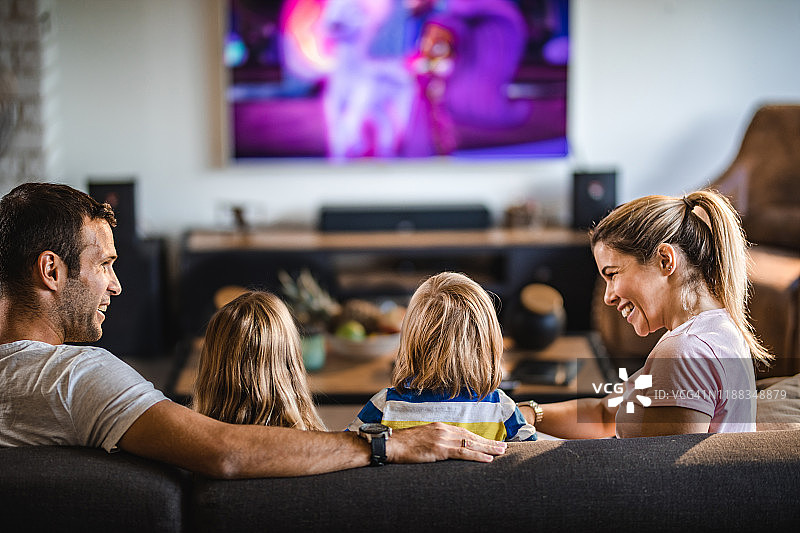 一家人在家里的沙发上看电视的背面图片素材