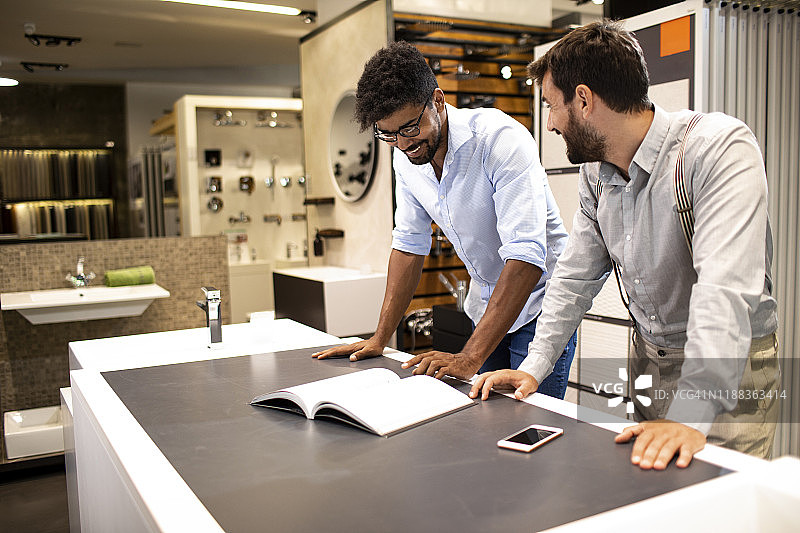 店主在卫浴设备专卖店帮助顾客规划浴室改造图片素材