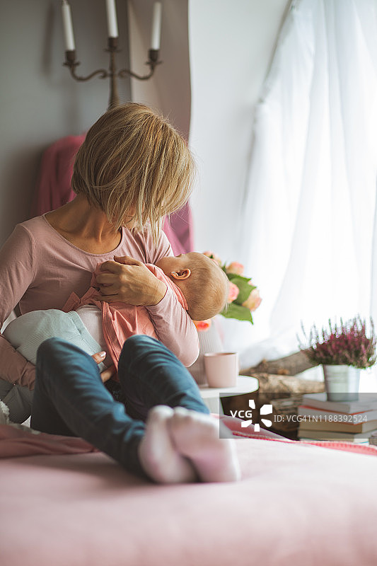 母亲抱着她的小宝宝，哄她入睡图片素材