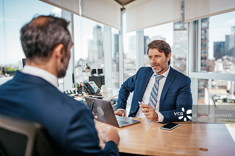 在办公室讨论合作关系的成熟商人图片素材