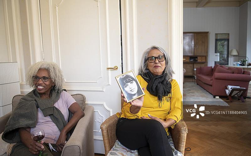 年长的女人展示自己年轻时的照片图片素材