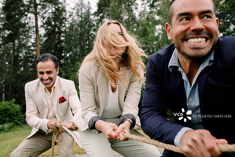 微笑的男女同事在玩拔河图片素材