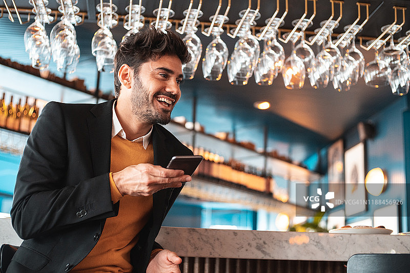男人坐在酒吧，用智能手机发送语音消息图片素材