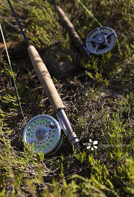 森林地面上的两根飞蝇钓竿，局部展示手柄、卷轴和钓线，海里耶达伦，瑞典图片素材