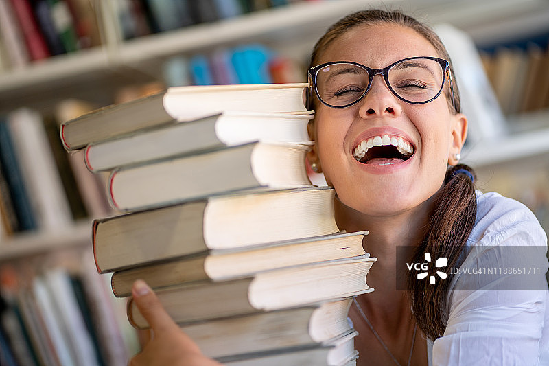 快乐的年轻女人抱着一堆书图片素材